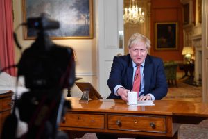 Boris Johnson bak skrivebordet - med videokamera rettet mot seg. foto